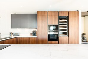 A modern kitchen with wooden cabinets, a built-in oven, and a coffee machine. - Luxury Villa Arizona - Sea View (Grimaud)