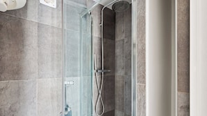 A glass-enclosed shower with a handheld showerhead and a wall-mounted faucet. - Studio Near Eiffel & Musée d'Orsay (Paris)
