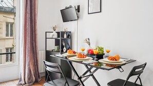 A dining area with a table set for two, featuring croissants, fruit, and orange juice. - Studio Near Eiffel & Musée d'Orsay (Paris)