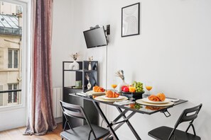 A dining area with a table set for two, featuring croissants, fruit, and orange juice. - Studio Near Eiffel & Musée d'Orsay (Paris)