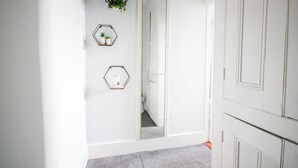 A hallway with a large mirror, three hexagonal wall decorations, and a white door. - Aura - Sleeps 6 - Free Parking (Folkestone)