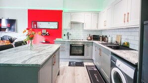 A modern kitchen with white cabinets, a built-in oven, a microwave, and a washing machine. - Aura - Sleeps 6 - Free Parking (Folkestone)