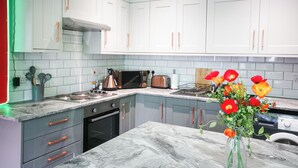 A modern kitchen with white cabinets, a marble countertop, and a vase of flowers. - Aura - Sleeps 6 - Free Parking (Folkestone)