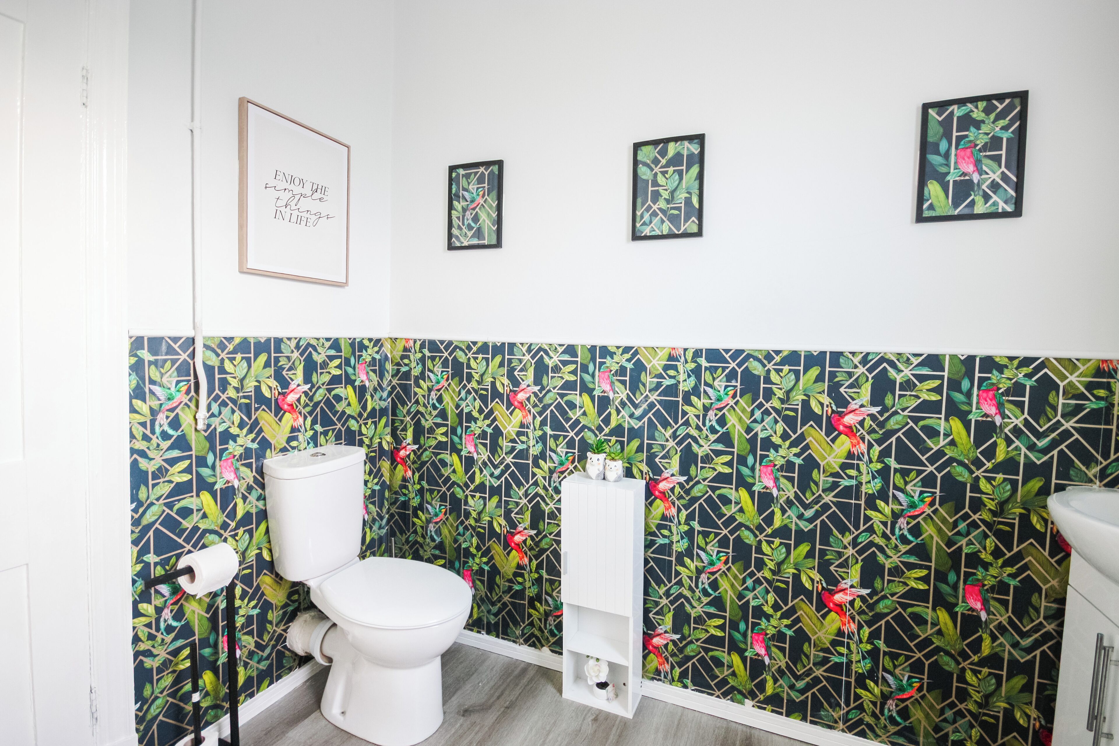 A bathroom with a toilet, a shelf with toiletries, and a wall with a floral pattern.