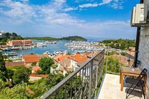 A balcony with a table and chairs overlooking a marina with boats and buildings. - Bella Vista Vrsar (Vrsar)