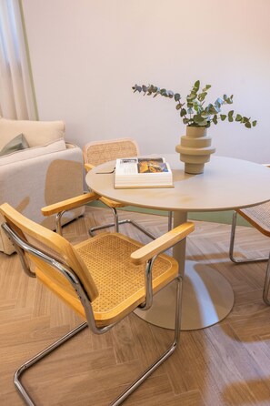 A round table with a book, a potted plant, and two chairs with woven seats. - 4Duques Apartments (Cáceres)