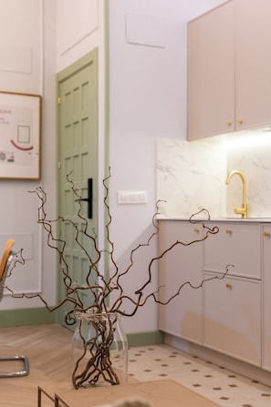 A kitchen with white cabinets, a green door, and a vase with branches on the counter. - 4Duques Apartments (Cáceres)