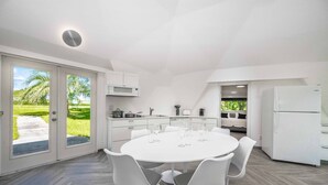 Una cocina moderna con comedor blanco, ventanas amplias y vistas a zonas verdes.