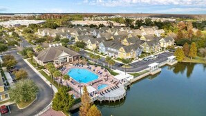 A residential area with houses, a swimming pool, and a dock extending into a lake. - Kissimmee 4BR l Resort Living l Great Location (Kissimmee)