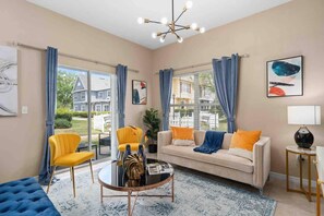 A living room with a sofa, two chairs, a coffee table, and a view of a house through large windows. - Kissimmee 4BR l Resort Living l Great Location (Kissimmee)