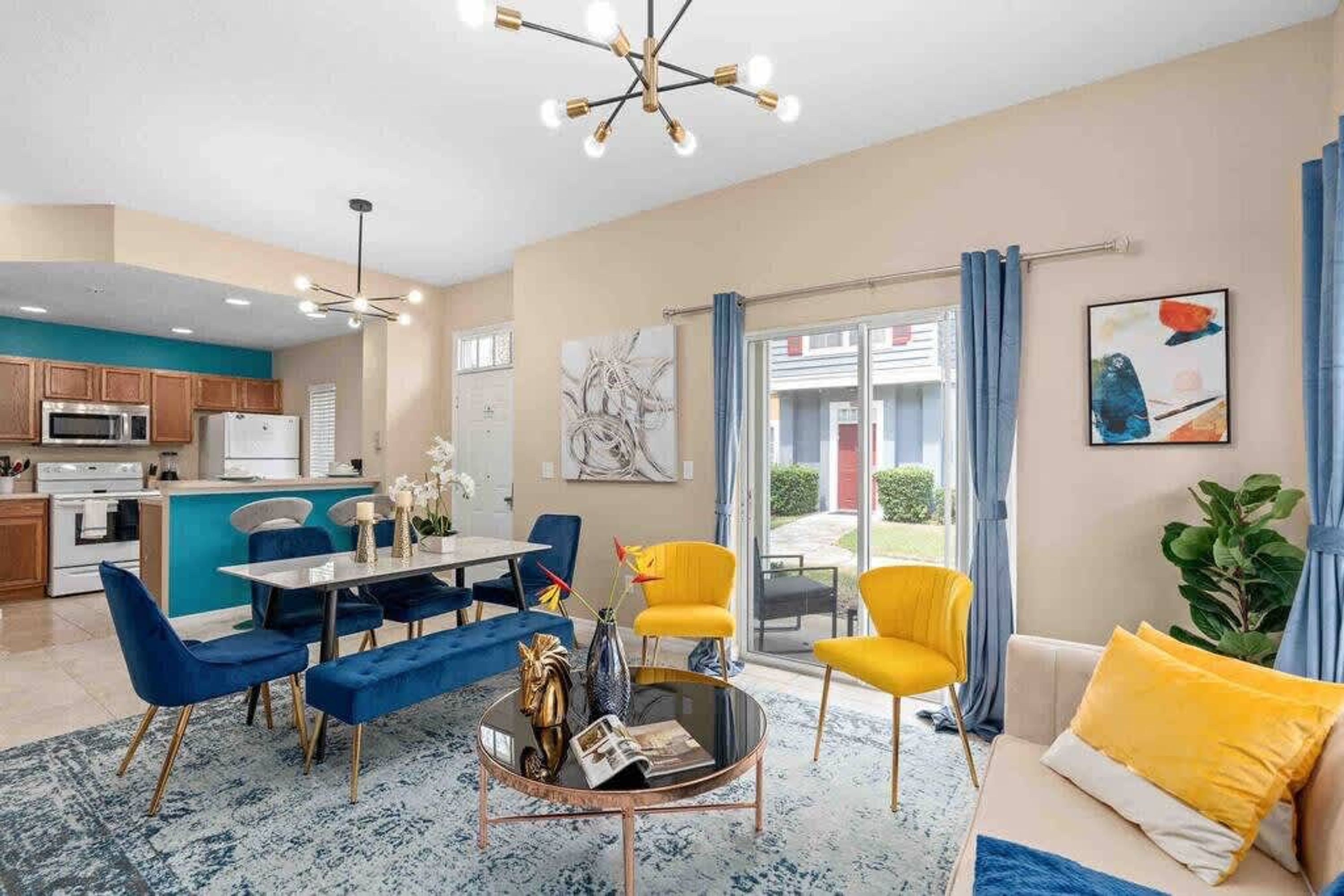 Una sala de estar moderna con comedor, cocina y vistas a través de puertas de vidrio.