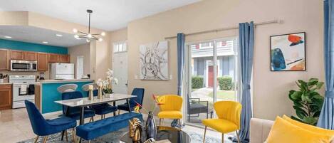 Una sala de estar moderna con comedor, cocina y vistas a través de puertas de vidrio.