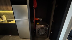 A compact kitchen with a refrigerator, a washing machine, and a small countertop with a kettle. - w Well-appointed 2BR w Balcony in Tabacalera (Mexico City)