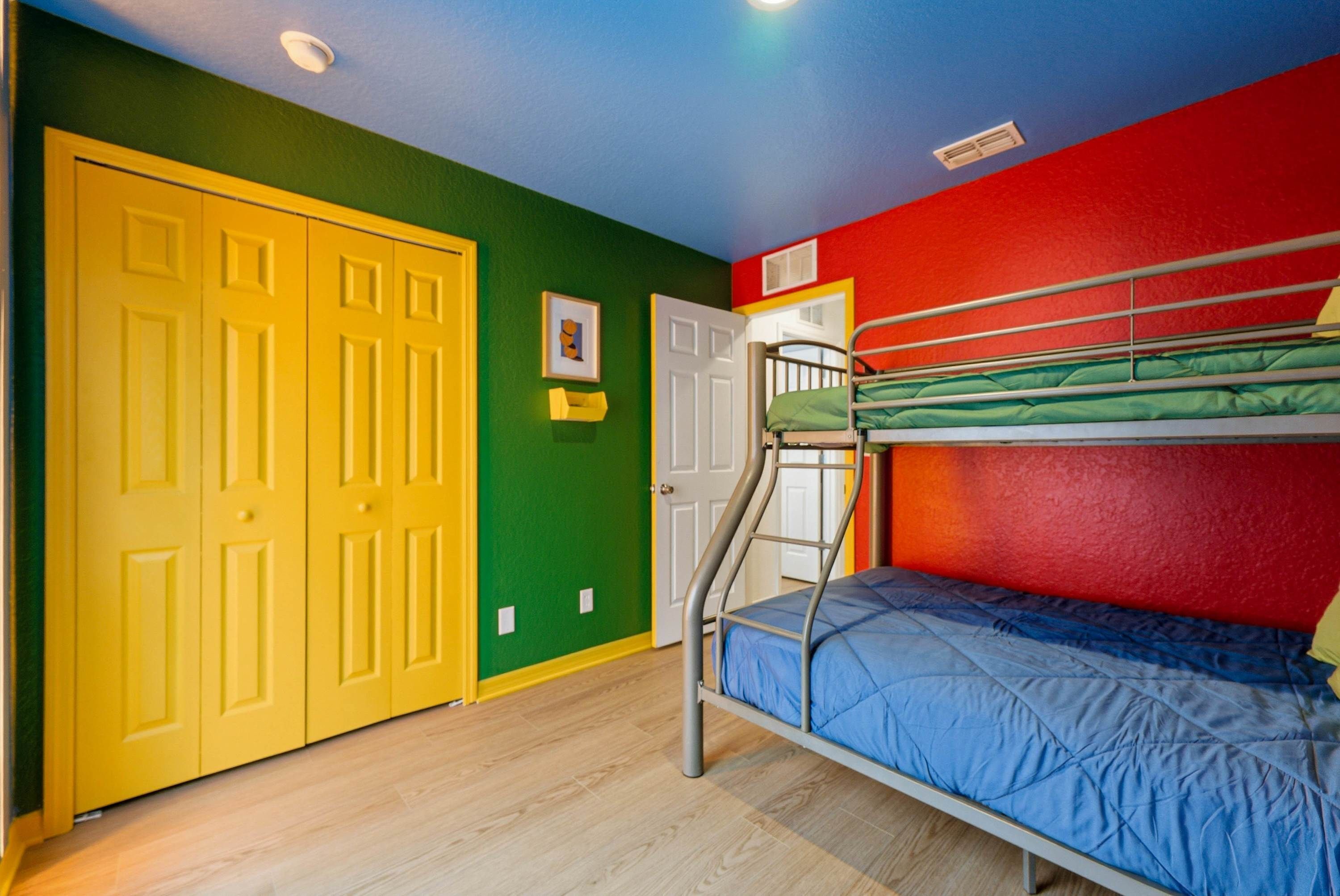 A room with a bunk bed, a yellow door, and green and red walls.