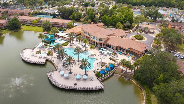 Ein Resort mit einem zentralen Pool, Palmen und Zugang zum Wasser.