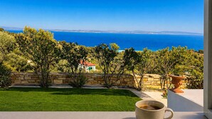 Un balcón con vista al mar, una taza de café y una pared de piedra.