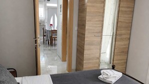 Un dormitorio con cama, armario y baño visible a través de una puerta abierta.