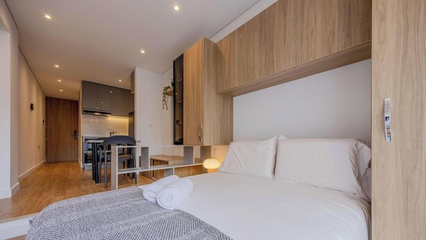 A modern hotel room with a bed, a desk, and a kitchenette. - NOK Bright 1BR Apartment Near Unicentro Bogot (Bogotá)