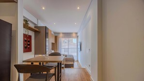 A modern hotel room with a dining area, a bed, and a TV mounted on the wall. - NOK Bright 1BR Apartment Near Unicentro Bogot (Bogotá)