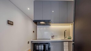A modern kitchen with a built-in microwave, a stove, and a range hood. - NOK Bright 1BR Apartment Near Unicentro Bogot (Bogotá)
