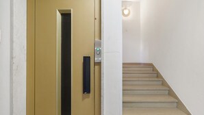 Una escalera que conduce a un ascensor, una puerta con manija y un accesorio de iluminación.