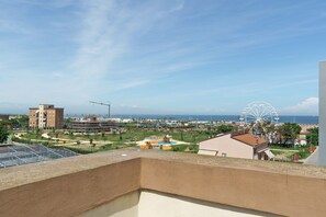 Ein Balkon mit Blick auf ein Riesenrad, einen Strand und einen Spielplatz.