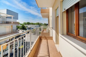 A balcony with a view of the street, a railing, and a building with a window. - Just Steps from the Beach – Cozy Apartment in Sottomarina (Chioggia)
