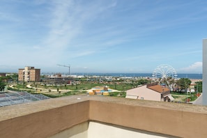 Ein Balkon mit Blick auf ein Riesenrad, einen Strand und einen Spielplatz.