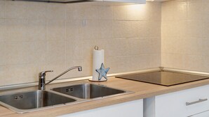 A kitchen with two stainless steel sinks, a wooden countertop, and a white cabinet with a handle. - Just Steps from the Beach – Cozy Apartment in Sottomarina (Chioggia)