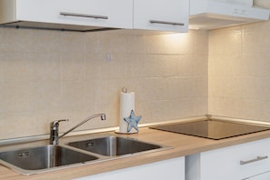 Una cucina con due lavelli in acciaio inossidabile, un piano di lavoro in legno e un armadietto bianco con maniglia.