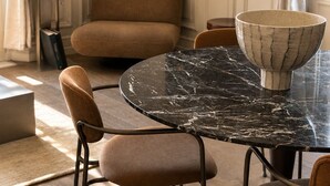 Un coin repas avec une table ronde en marbre, des chaises rembourrées et un saladier posé sur la table.