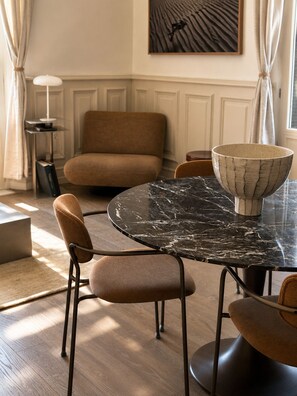 Un coin repas avec une table ronde en marbre, des chaises rembourrées et un saladier posé sur la table.