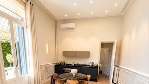 Un salon moderne comprenant un canapé, une table à manger avec des chaises, un coin cuisine avec des placards et une grande fenêtre agrémentée de rideaux.