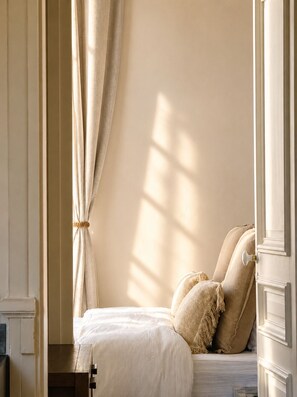 A bedroom with a bed, curtains, and a nightstand.
