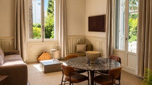 Une pièce spacieuse avec une table de salle à manger ronde, un canapé et une grande fenêtre avec des rideaux.