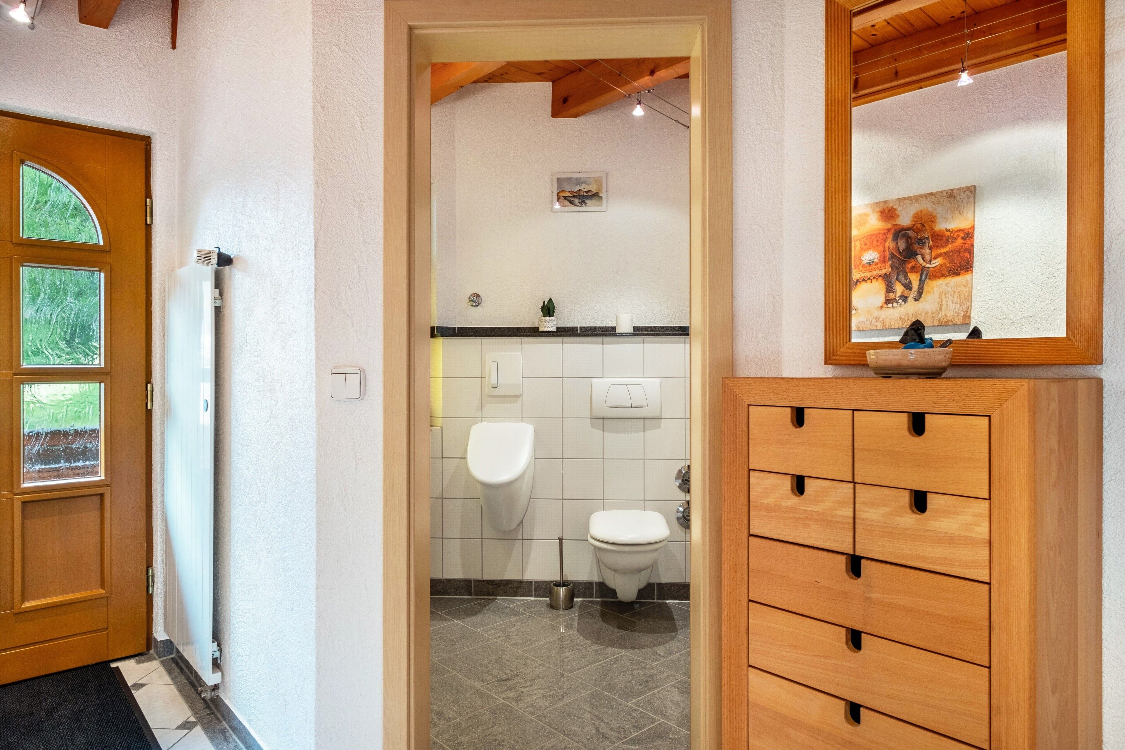 A bathroom with a toilet, bidet, and a wooden cabinet with drawers.