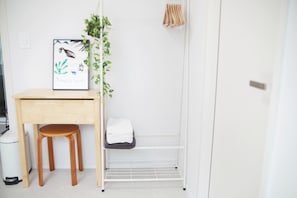 A clean, minimalistic room with a wooden desk, a chair, a white shelf, a framed picture, and a hanging plant. - Peaceful 3-Bedroom Stay with 2 Baths near KSPO Dome & Olympic Park (Seoul)