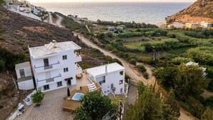 Un edificio blanco con balcones, piscina y vista al mar.