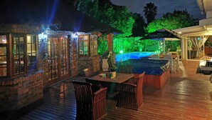 Eine Terrasse im Freien mit Pool, Holzdeck und Barbereich.