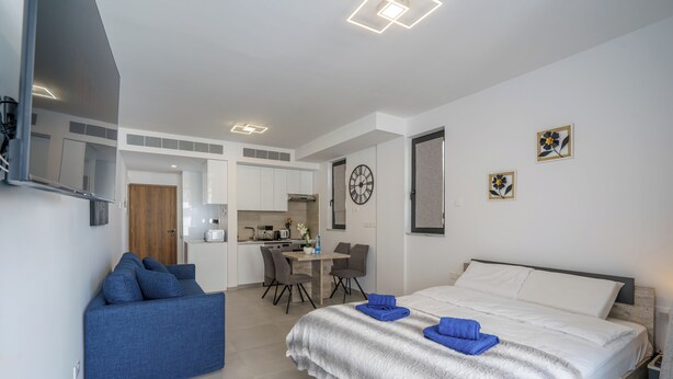Une chambre d’hôtel moderne équipée d’un lit, d’un canapé, d’un coin repas et d’une cuisine.