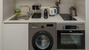 Une cuisine compacte équipée d’un lave-linge, d’un lave-vaisselle et d’un four.