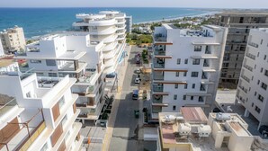 Un immeuble résidentiel de grande hauteur, doté de balcons, donnant sur une rue et offrant une vue sur la mer.