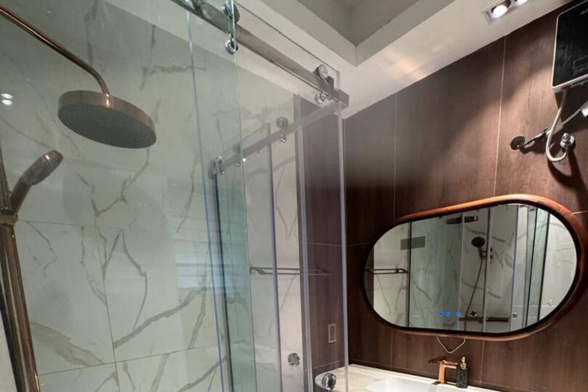 Un bagno moderno con cabina doccia in vetro, un mobile lavabo e un grande specchio.