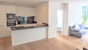 A modern kitchen with white cabinets, a black countertop, and stainless steel appliances. - 12-guest Apartment on the Main Square (Antwerp)