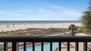 A beach view from a balcony with a pool and lounge chairs. - Romar House 304A by Liquid Life (Orange Beach)