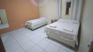 Una habitación de hotel con una cama, una cama individual, una mesita de noche, aire acondicionado y una ventana con cortinas.