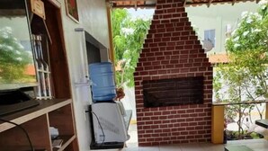 Una cocina con pared de ladrillo, dispensador de agua, pileta y piso con baldosas.