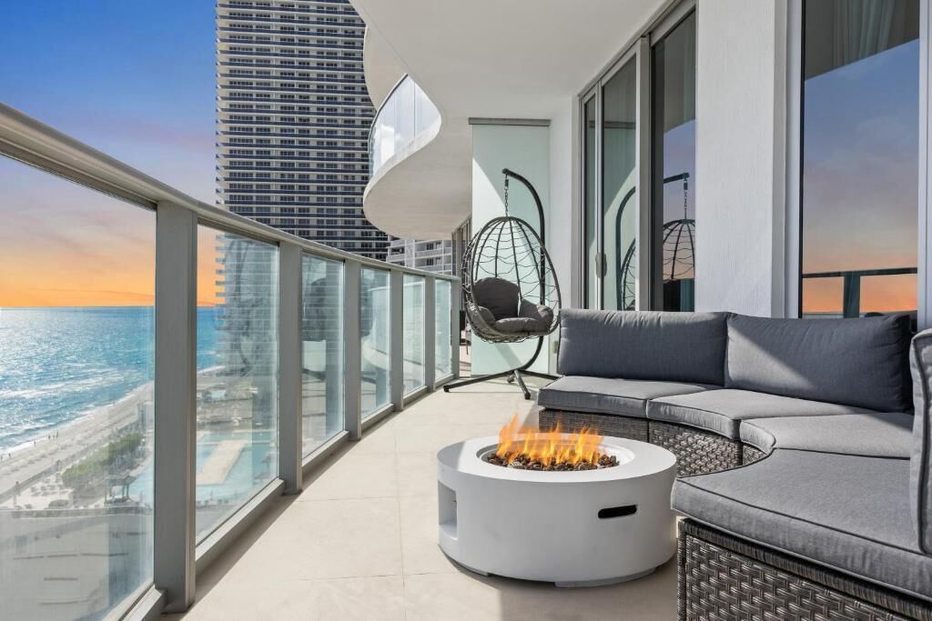 Ein Balkon mit Feuerstelle, Sitzgelegenheiten und Blick auf den Ozean.