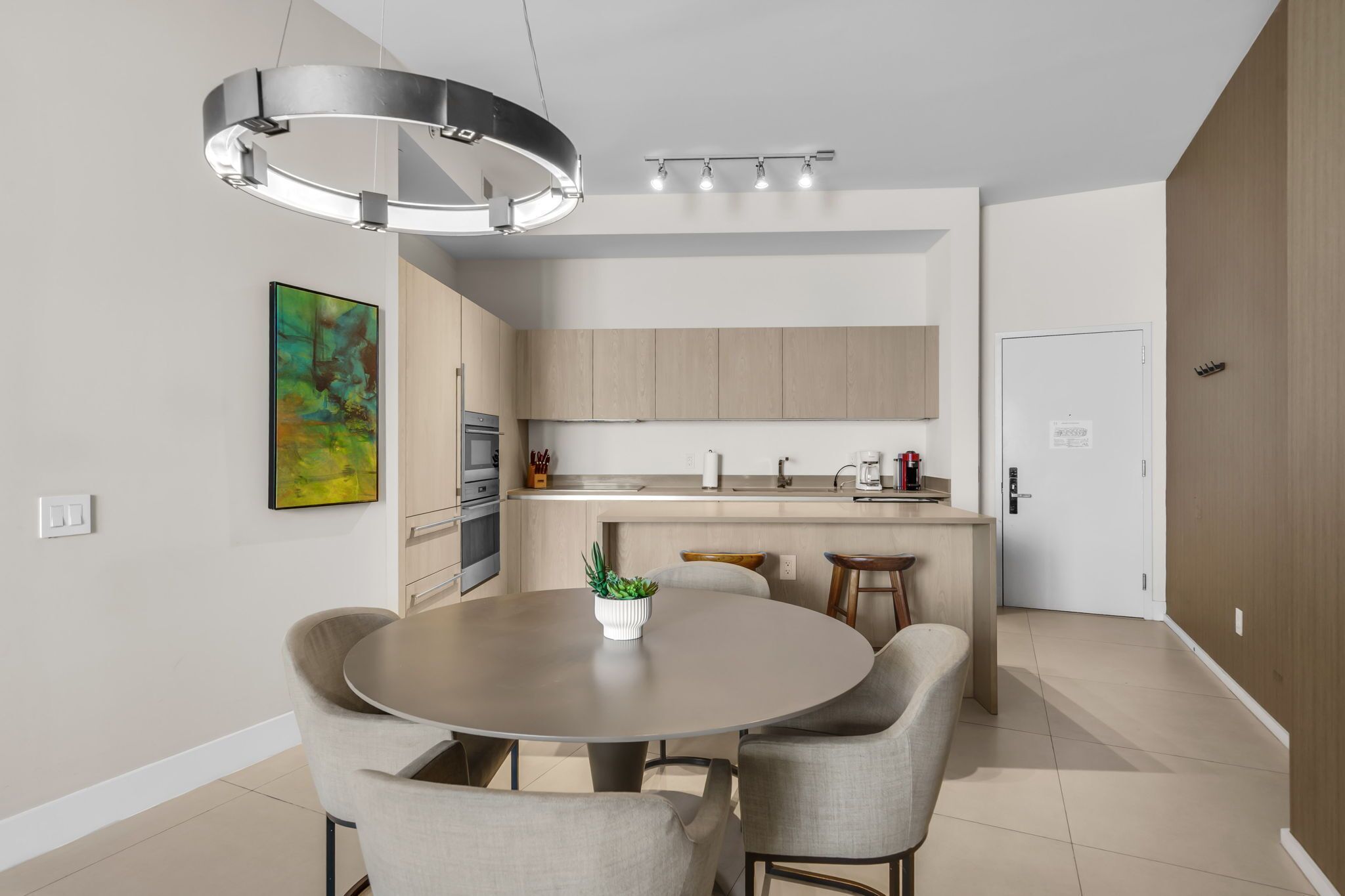 Une cuisine moderne dotée d’un îlot central, d’un coin repas avec une table ronde et d’un luminaire suspendu au-dessus.