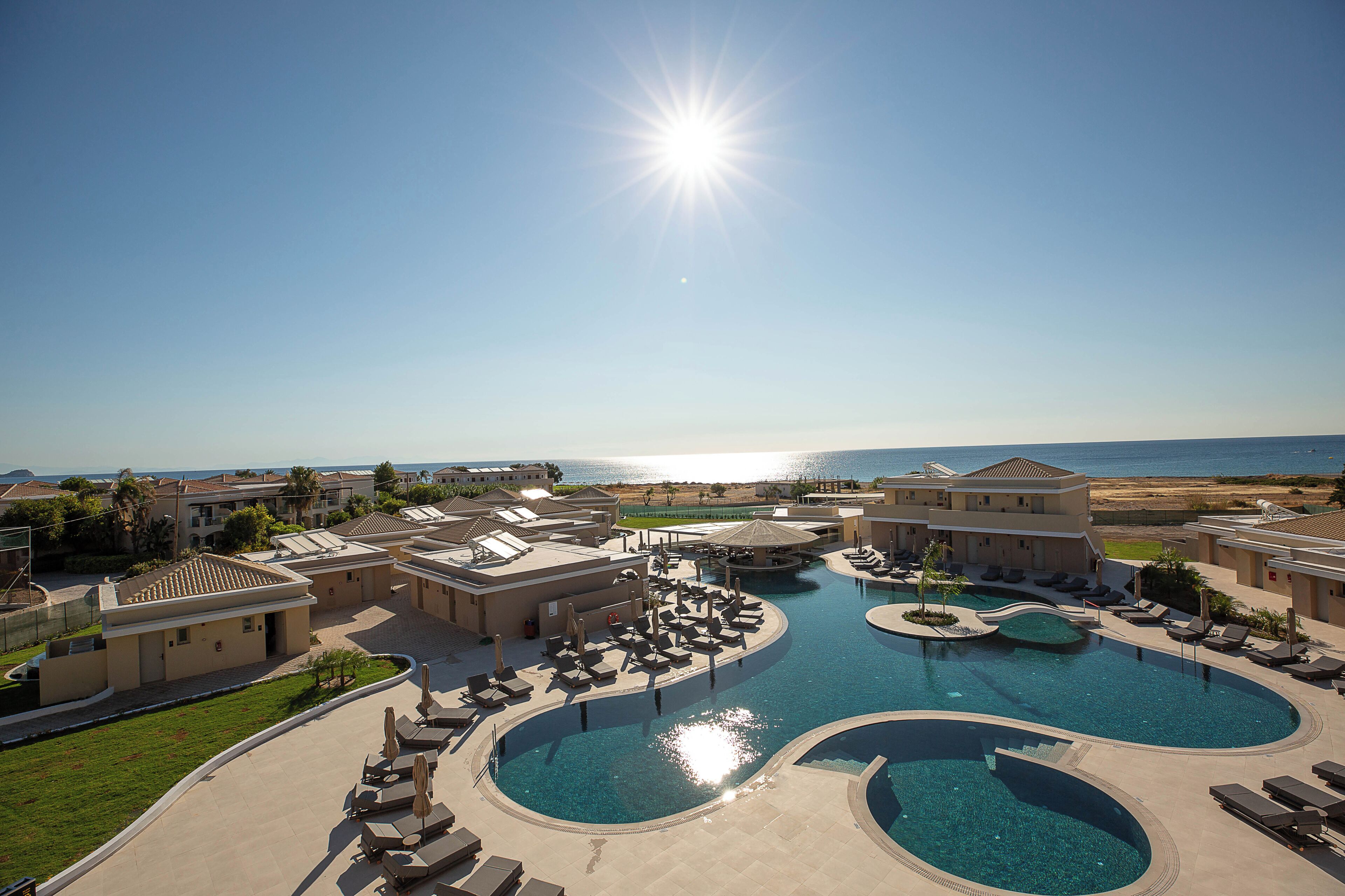 Un resort con varias piscinas, tumbonas y vistas al mar.